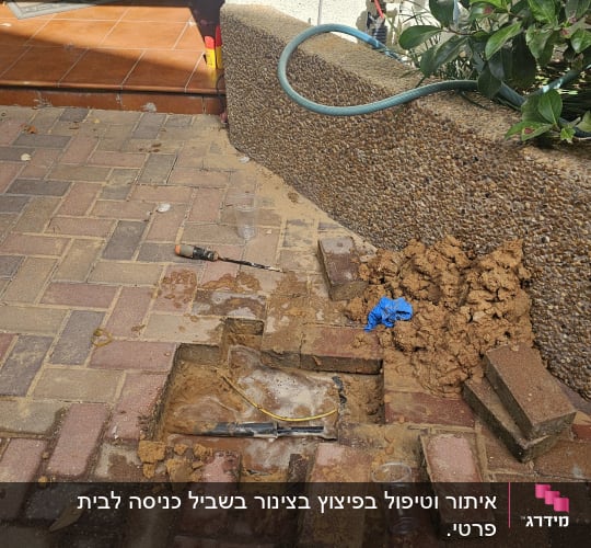 חפירה וחשיפת צנרת מים מתחת לאבנים משתלבות בחצר לצורך תיקון